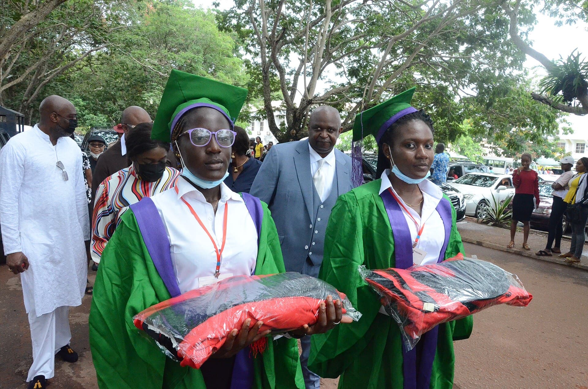 Two graduates in the University of Nigeria’s green convocation gowns, walking to the ceremony